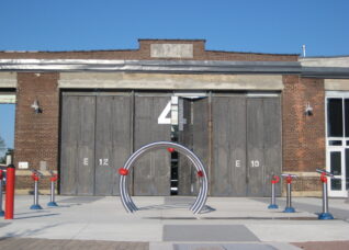 View of barn doors and public art of metal bars arching