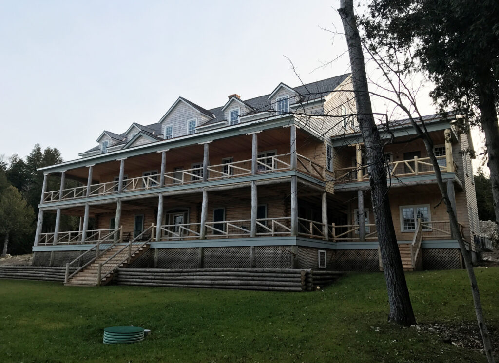exterior of a wooden, three story lakeside building with large balconies on the first and second levels