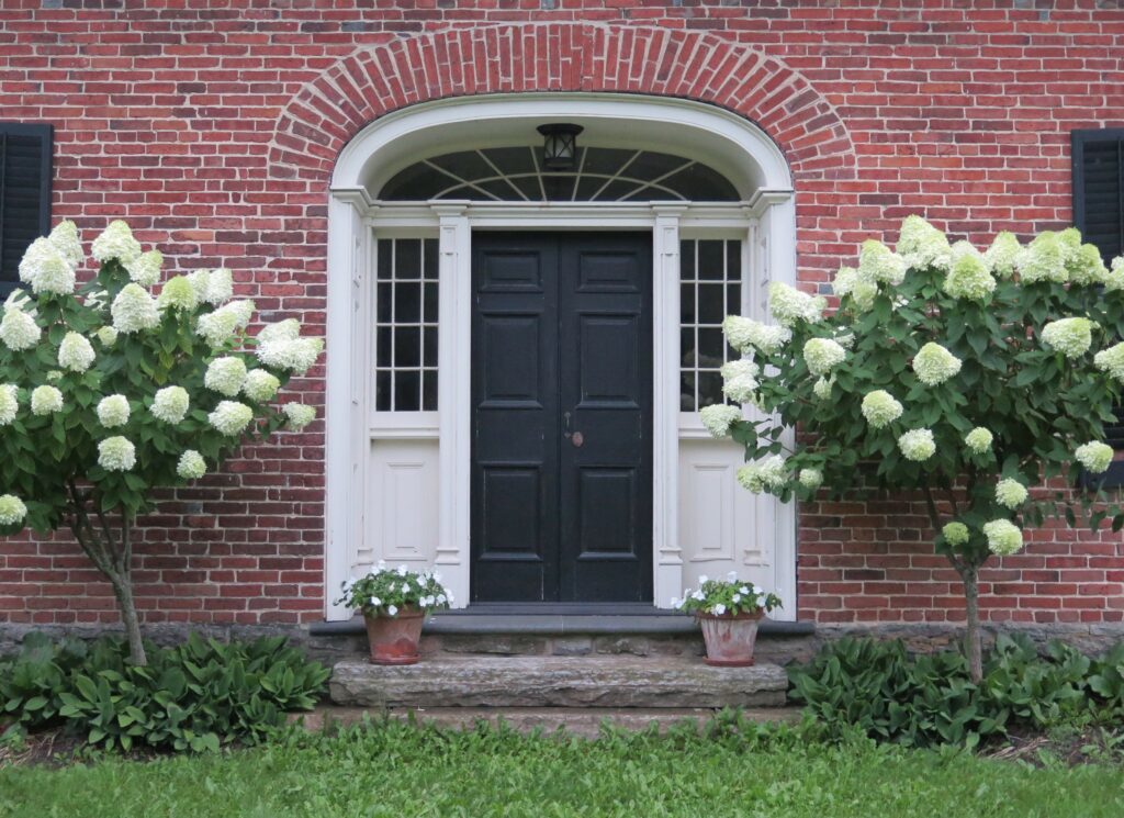 exterior view of a door with surrounding glass panes, and an arched brick entranceway