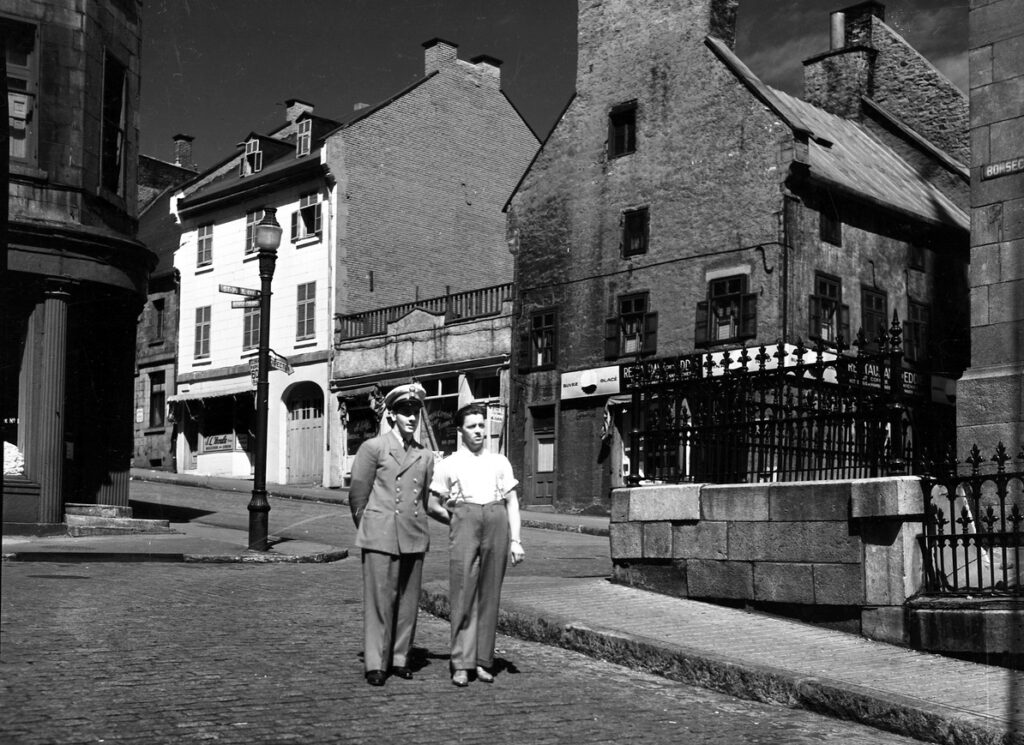 Archival photo of historic stone buildings with people out front