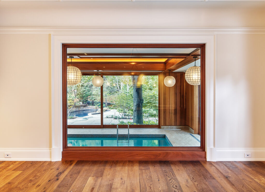 a symmetrical photo looking through an interior window into a room with an indoor pool